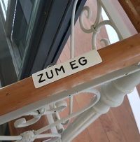 Weißes Handlaufschild mit taktiler Profilschrift in schwarz Weißes Handlaufschild mit taktiler Profilschrift in schwarz